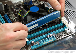 Person installing a memory chip on a motherboard.