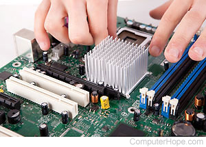 Hands working with a computer motherboard.
