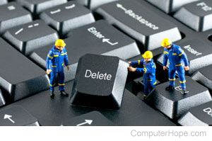 Mini construction workers removing the Delete key from a keyboard.